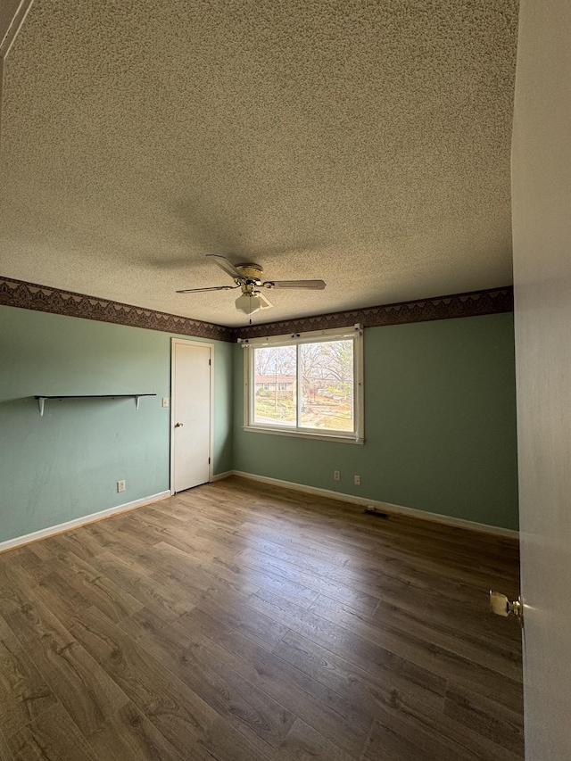 spare room with a textured ceiling, hardwood / wood-style flooring, and ceiling fan