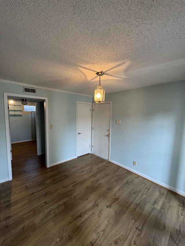 empty room featuring dark hardwood / wood-style floors, a textured ceiling, and ornamental molding