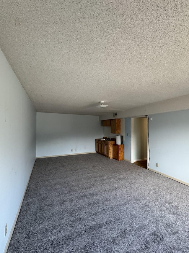 unfurnished living room with dark carpet and a textured ceiling