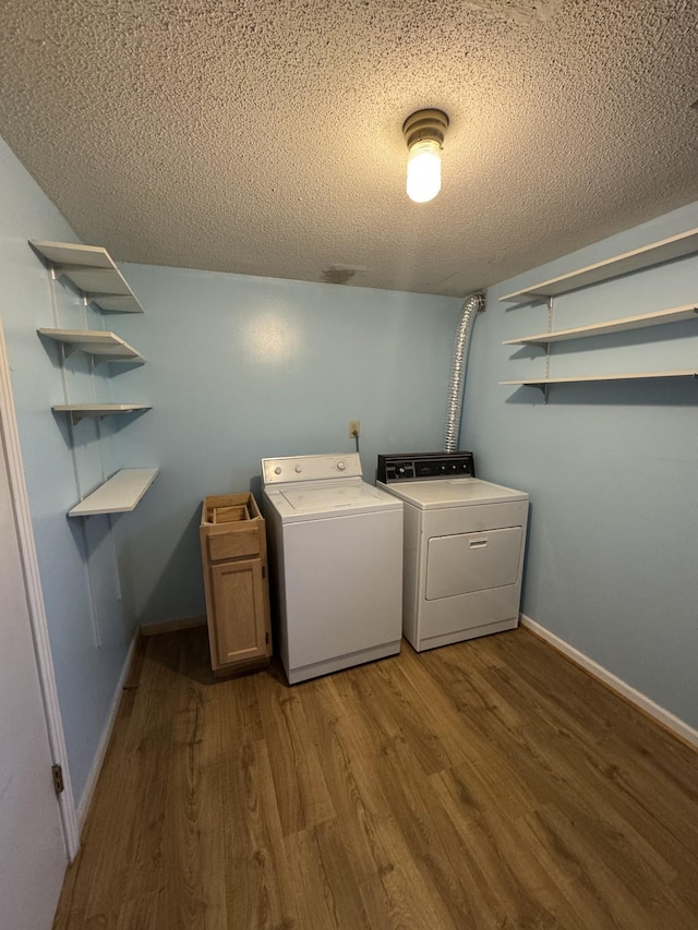 laundry area featuring hardwood / wood-style flooring, cabinets, independent washer and dryer, and a textured ceiling