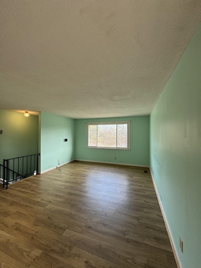 empty room featuring a textured ceiling and dark hardwood / wood-style floors