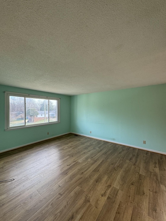 spare room featuring a textured ceiling and hardwood / wood-style flooring