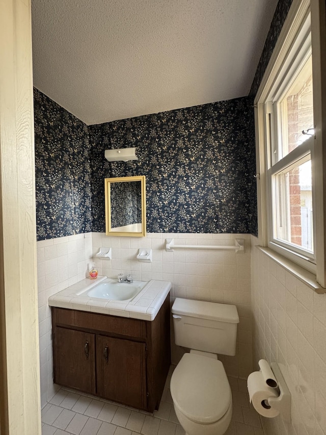 bathroom with tile patterned floors, vanity, toilet, and a textured ceiling