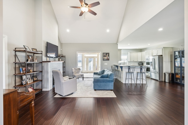 living room with dark hardwood / wood-style floors, ceiling fan, and high vaulted ceiling