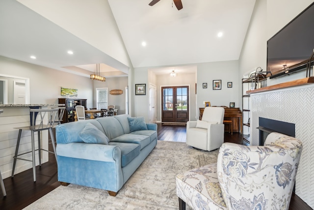 living room with a tiled fireplace, ceiling fan, high vaulted ceiling, and wood-type flooring