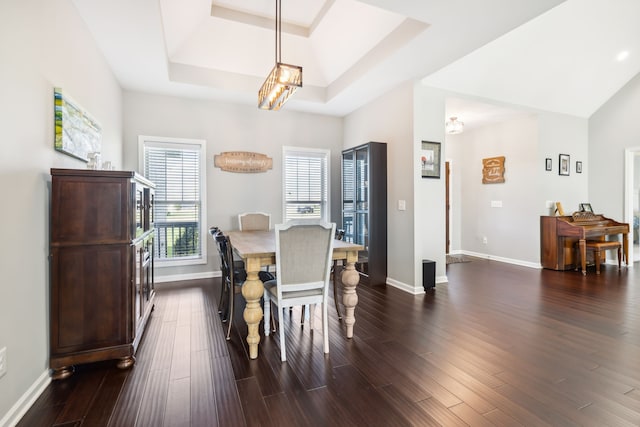 dining space featuring a notable chandelier, dark hardwood / wood-style flooring, and a tray ceiling