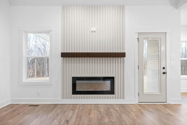 unfurnished living room featuring heating unit and wood-type flooring