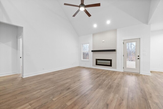 unfurnished living room featuring ceiling fan, high vaulted ceiling, a fireplace, and light hardwood / wood-style floors