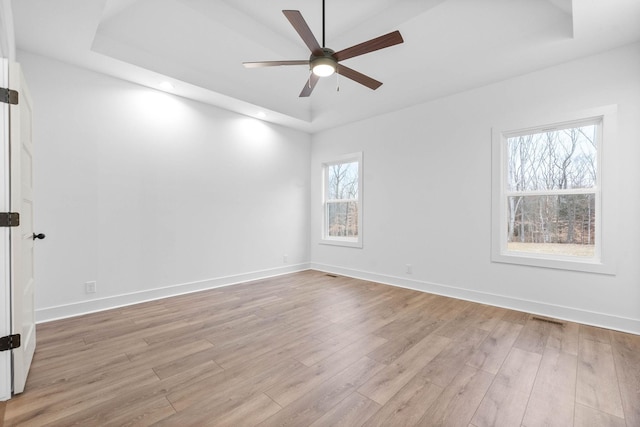 empty room featuring light hardwood / wood-style floors, a raised ceiling, and ceiling fan