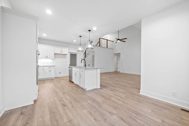 kitchen with white cabinetry, light stone counters, hanging light fixtures, a center island with sink, and stainless steel dishwasher