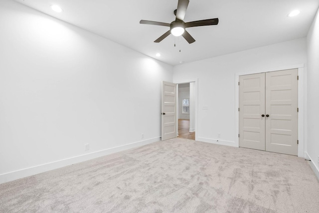 unfurnished bedroom featuring light carpet, ceiling fan, and a closet