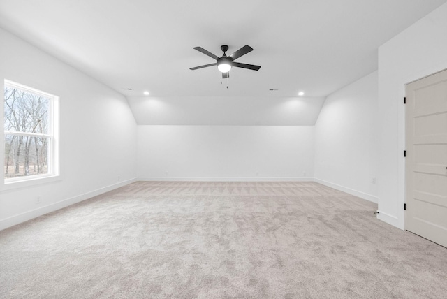 empty room with vaulted ceiling, ceiling fan, and light colored carpet