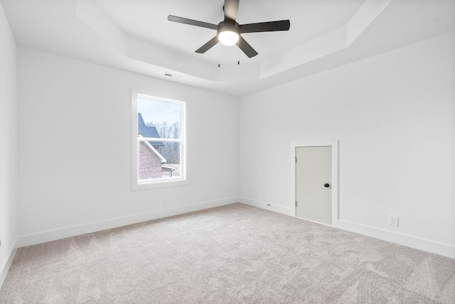 spare room with ceiling fan, a raised ceiling, and carpet floors