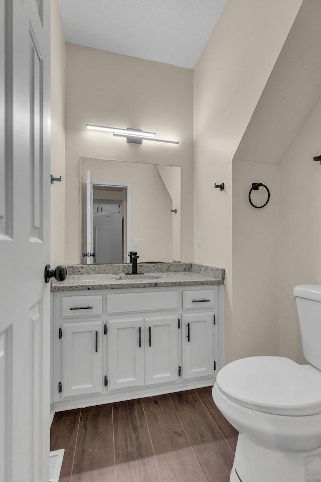 bathroom with hardwood / wood-style floors, vanity, and toilet