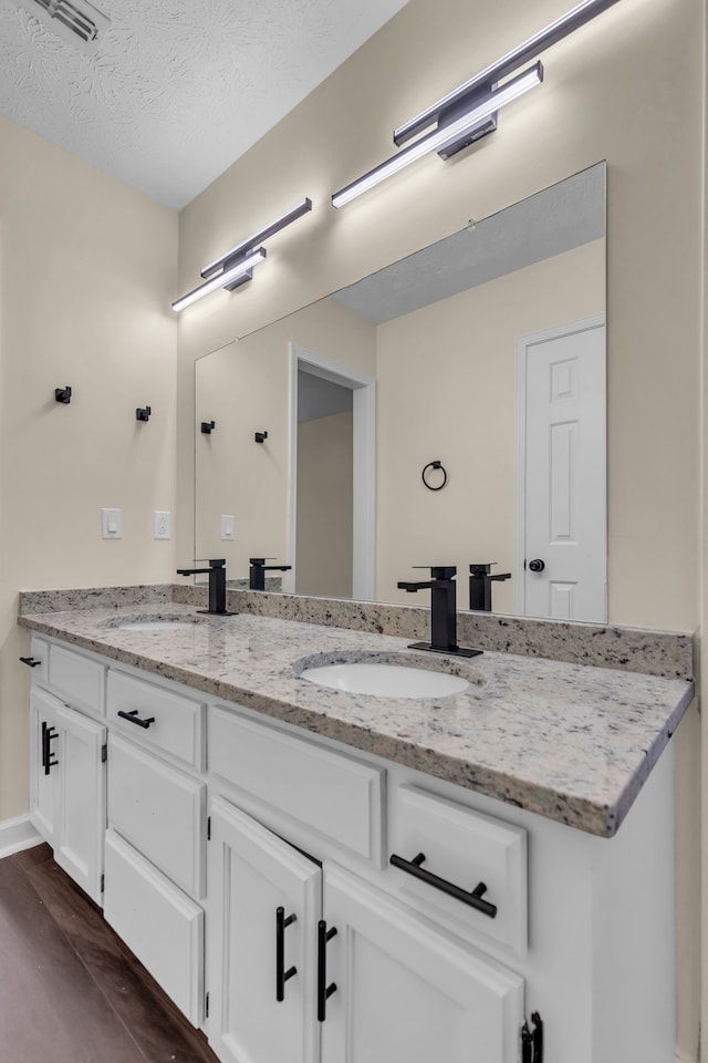 bathroom with vanity, a textured ceiling, and hardwood / wood-style flooring