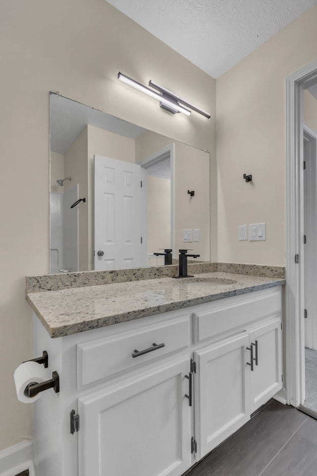 bathroom with vanity, a textured ceiling, and walk in shower