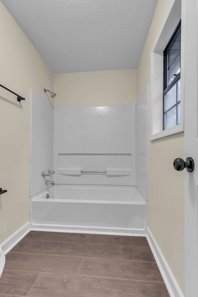 bathroom with shower / washtub combination and a textured ceiling