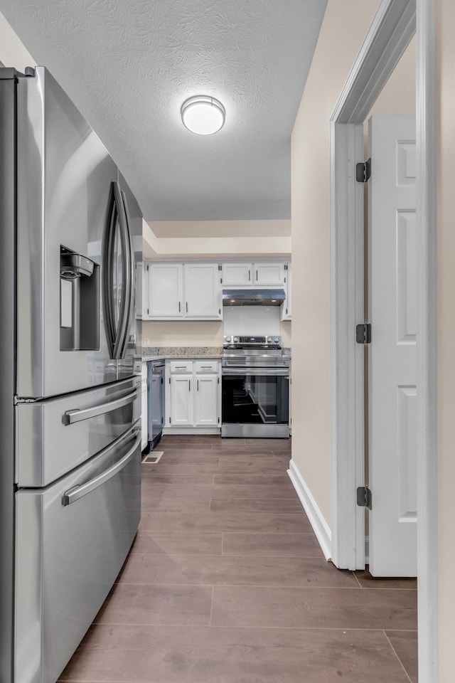 kitchen featuring light hardwood / wood-style flooring, white cabinets, stainless steel appliances, and a textured ceiling