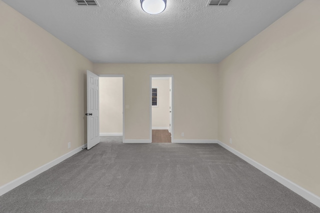 carpeted spare room featuring a textured ceiling