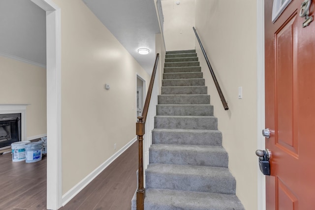 stairway featuring crown molding and wood-type flooring