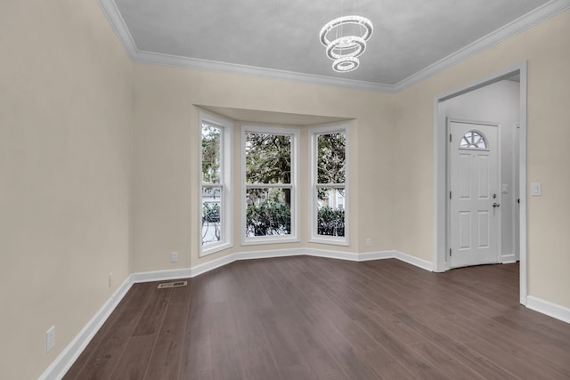 empty room featuring a chandelier, dark hardwood / wood-style floors, and crown molding