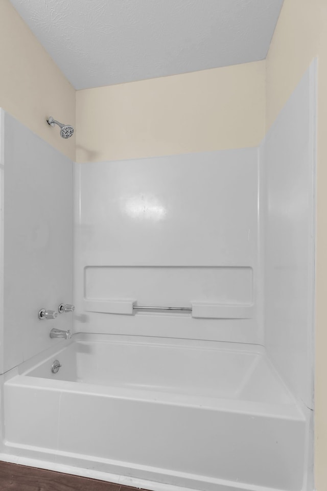 bathroom with washtub / shower combination and a textured ceiling