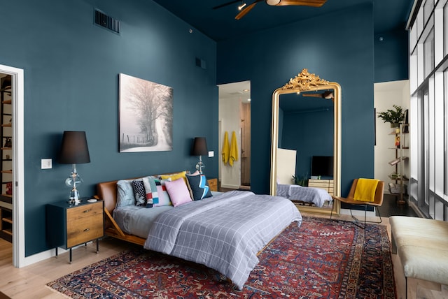 bedroom with a high ceiling, hardwood / wood-style flooring, and ceiling fan