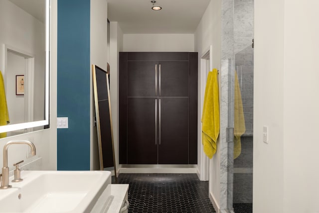 bathroom featuring tile patterned flooring, a tile shower, and sink