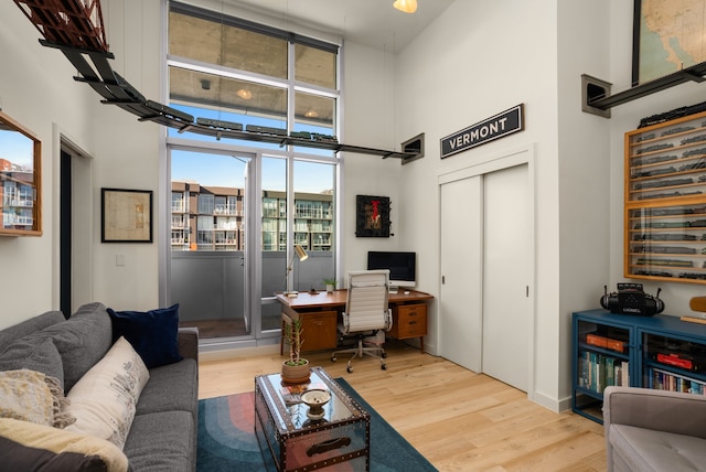 home office featuring wood-type flooring and a towering ceiling