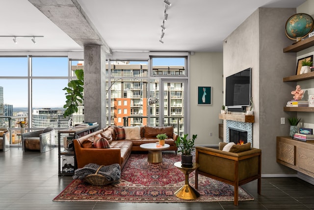 living room featuring a fireplace, track lighting, and a wall of windows