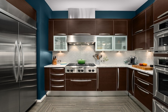 kitchen featuring dark brown cabinetry, extractor fan, appliances with stainless steel finishes, and tasteful backsplash