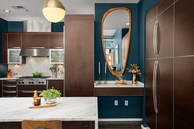 kitchen featuring decorative backsplash, appliances with stainless steel finishes, light stone counters, dark brown cabinets, and exhaust hood