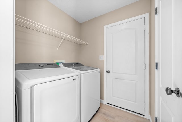 laundry room with separate washer and dryer, a textured ceiling, and light wood-type flooring