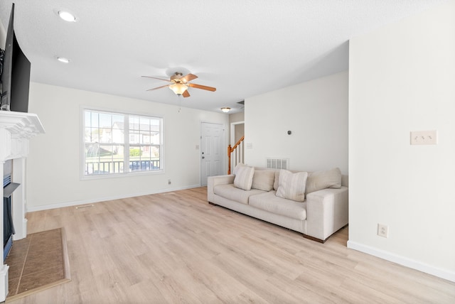 unfurnished living room with a textured ceiling, light wood-type flooring, and ceiling fan