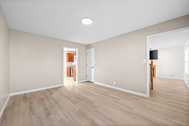 spare room featuring a textured ceiling and light hardwood / wood-style flooring