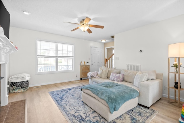 living room featuring a textured ceiling, light hardwood / wood-style flooring, and ceiling fan