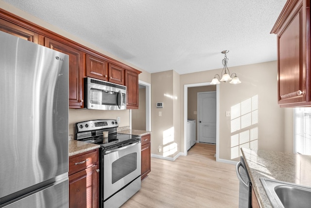 kitchen with appliances with stainless steel finishes, a textured ceiling, decorative light fixtures, a chandelier, and light hardwood / wood-style floors