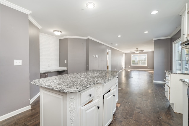 kitchen featuring ceiling fan, a center island, light stone counters, dark hardwood / wood-style flooring, and white cabinets