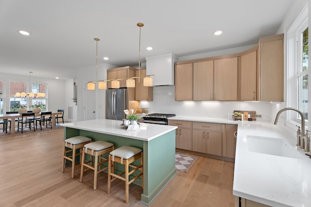 kitchen with a healthy amount of sunlight, a center island, stainless steel appliances, and light brown cabinets