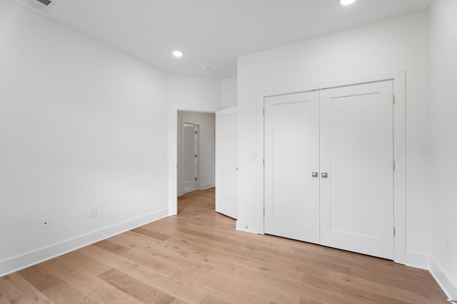 unfurnished bedroom with a closet and light wood-type flooring