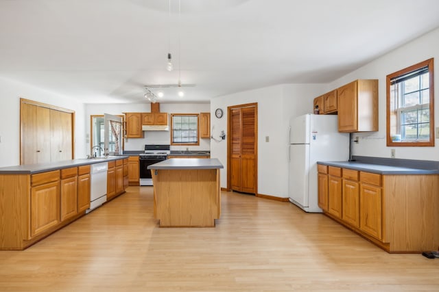 kitchen with sink, a kitchen island, white appliances, and light wood-type flooring