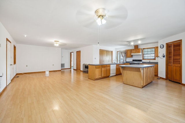 kitchen with white dishwasher, light hardwood / wood-style flooring, ceiling fan, a kitchen island, and kitchen peninsula