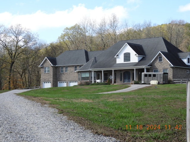 view of front of house featuring covered porch, a garage, and a front lawn