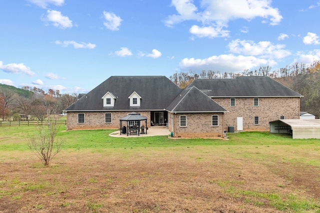 back of property with a gazebo, a patio area, and a lawn