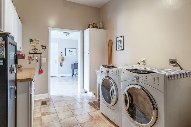 washroom with cabinets, washing machine and dryer, and light tile patterned flooring