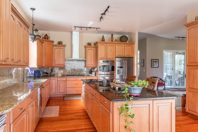 kitchen featuring light wood-type flooring, a center island with sink, stainless steel appliances, and wall chimney exhaust hood