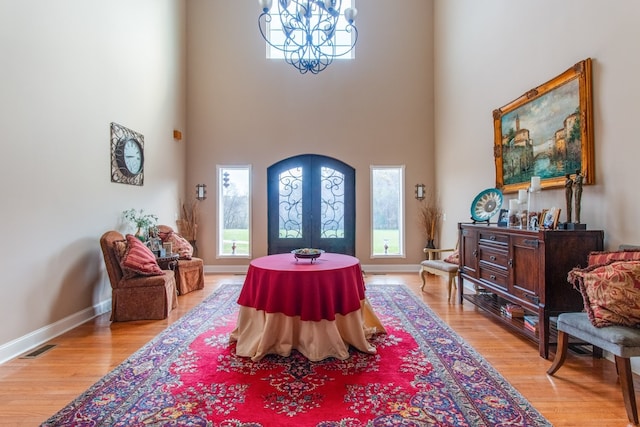 entryway featuring a chandelier, light wood-type flooring, a high ceiling, and french doors