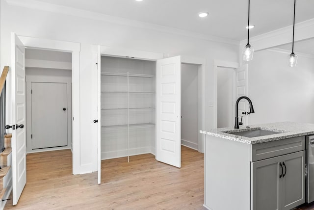 kitchen featuring gray cabinetry, sink, light wood-type flooring, decorative light fixtures, and light stone counters