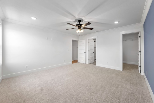 unfurnished bedroom with light carpet, ceiling fan, crown molding, a spacious closet, and a closet