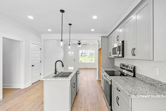 kitchen with appliances with stainless steel finishes, ceiling fan, sink, decorative light fixtures, and a center island with sink